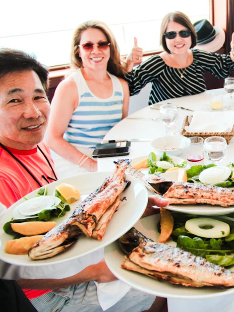 Guests enjoying grilled fish lunch on Bosphorus cruise towards the Black Sea.