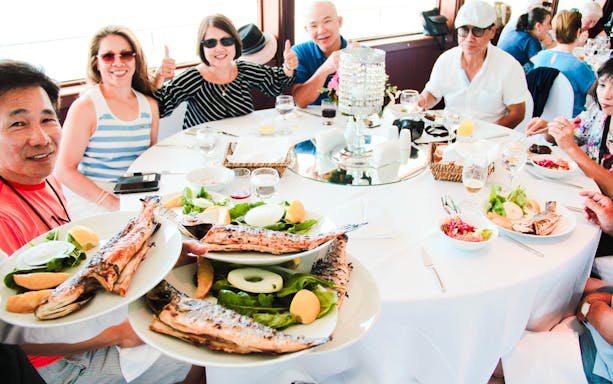 Guests enjoying grilled fish lunch on Bosphorus cruise towards the Black Sea.