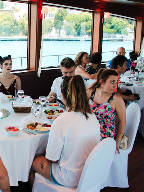 Guests enjoying lunch on a Bosphorus cruise with views of Istanbul's waterfront.