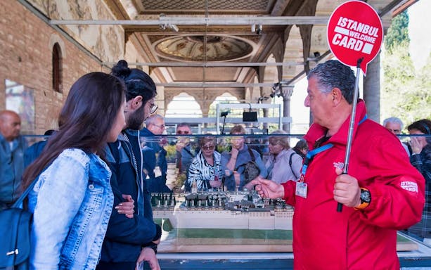 Tour guide explaining Topkapi Palace model to visitors in Istanbul.