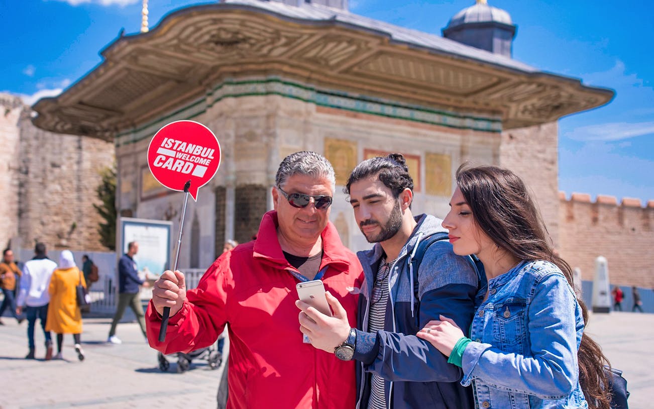 Visitors with guide at Topkapi Palace entrance, Istanbul, holding welcome card.