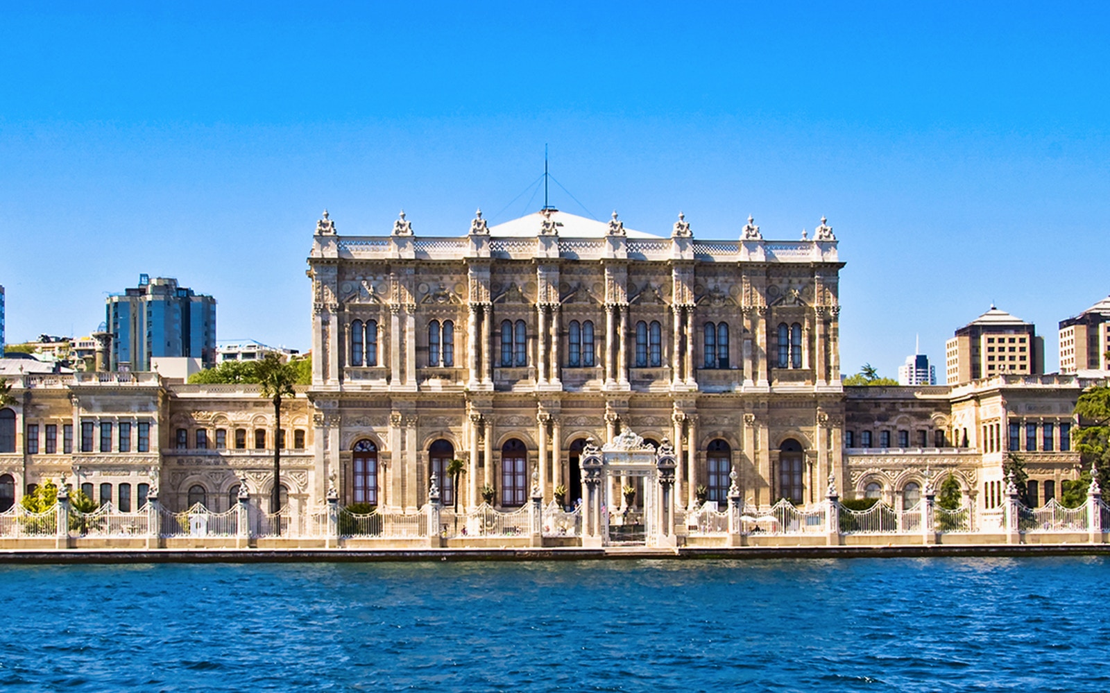 Dolmabahce Palace exterior with tourists using audio guides in Istanbul.