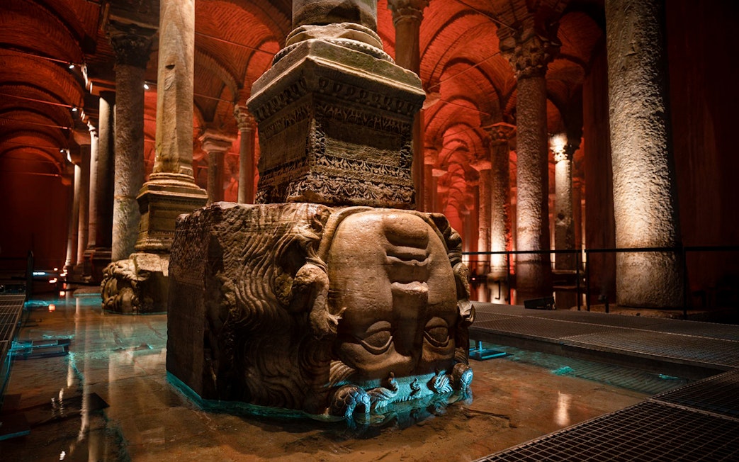 Guided tour group exploring Basilica Cistern in Istanbul with Medusa head column.