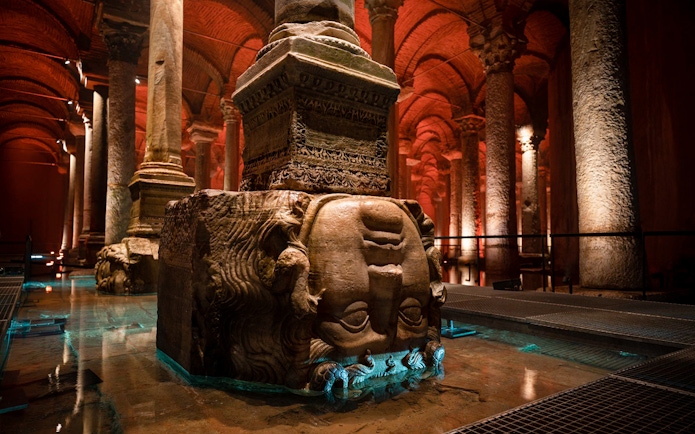 Guided tour group exploring Basilica Cistern in Istanbul with Medusa head column.