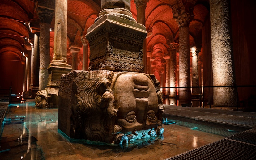 Guided tour group exploring Basilica Cistern in Istanbul with Medusa head column.