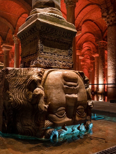 Guided tour group exploring Basilica Cistern in Istanbul with Medusa head column.