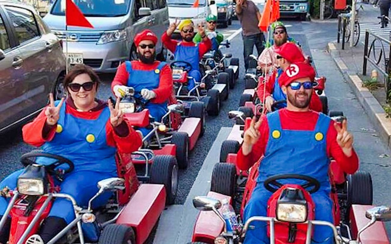Group in costumes driving go-karts on Tokyo street during Akihabara tour.
