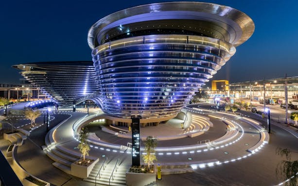Futuristic pavilion at Expo 2020 Dubai, illuminated at night with curved architecture.