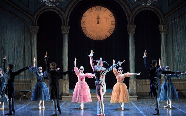 Ballet dancers in colorful costumes perform on stage with a large clock backdrop during "My First Ballet: Cinderella.