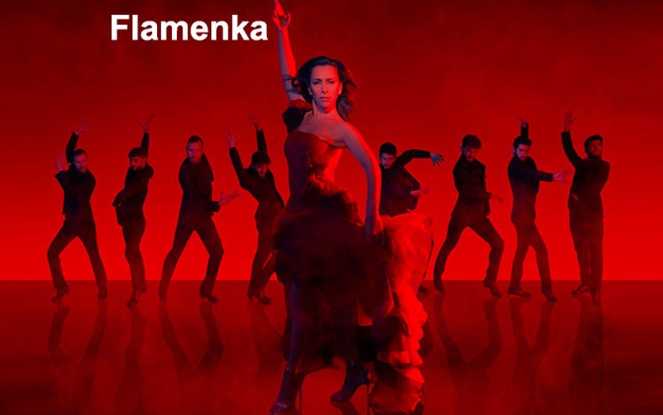 Flamenco dancers performing on stage with vibrant red background.