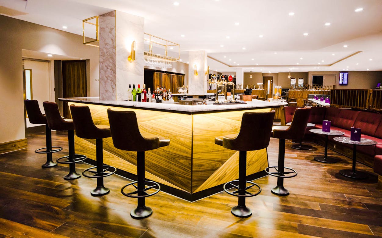 Bar area in Gatwick Airport Lounge, South Terminal, with seating and drinks display.