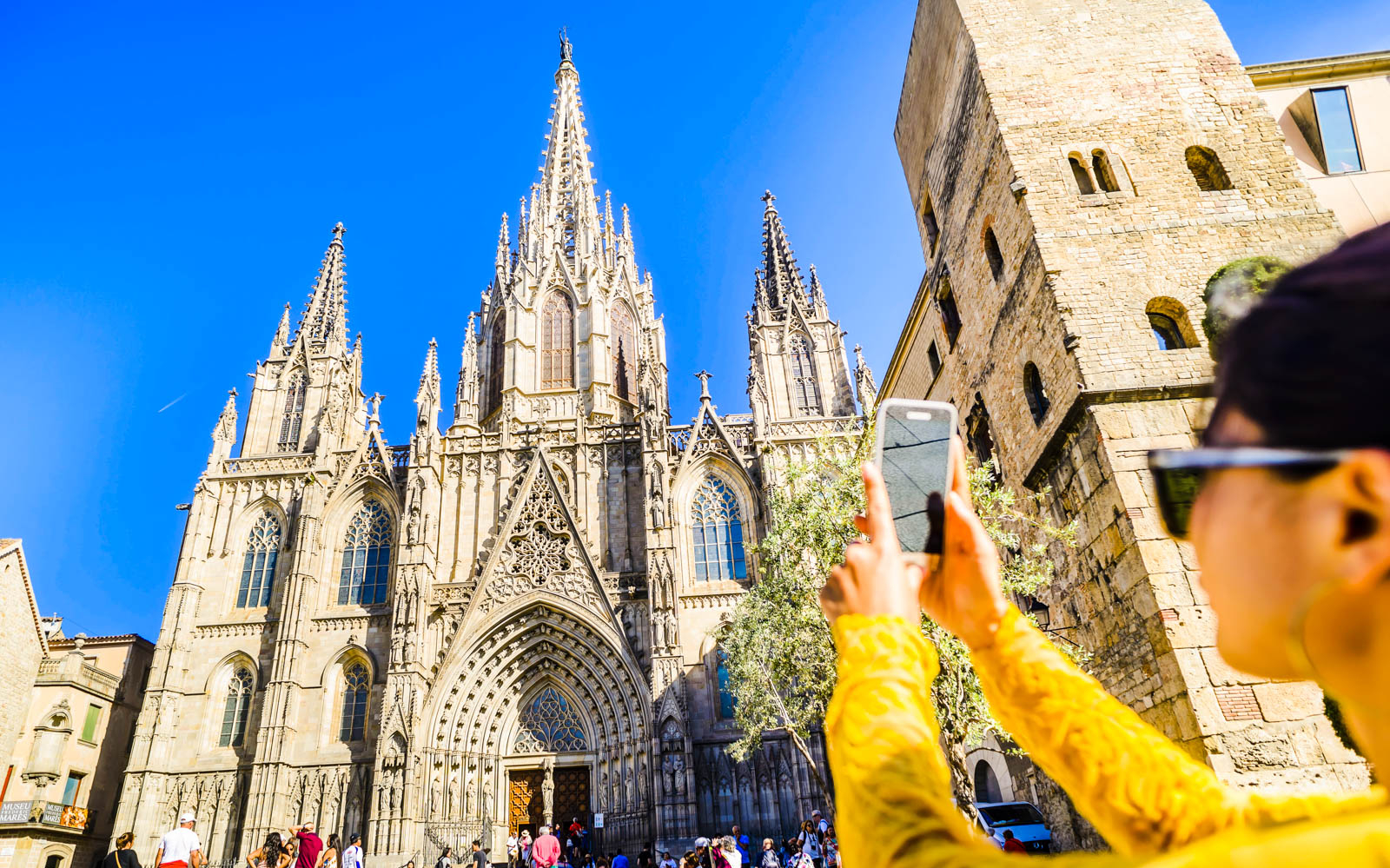 Barcelona Cathedral with tourist taking photo, part of Helicopter Flight, Walking Tour, & Boat Cruise.