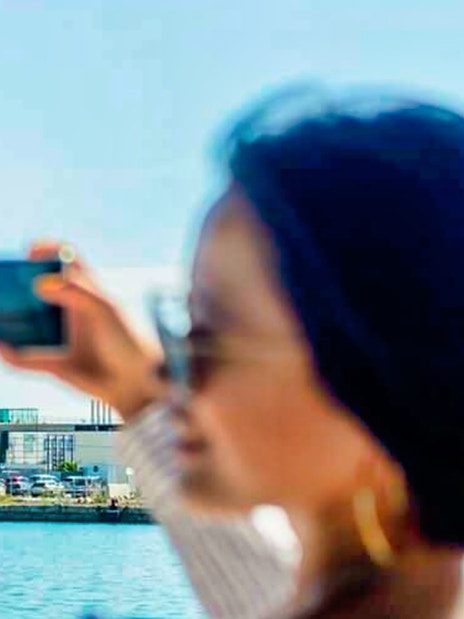 Barcelona waterfront view with a person taking a photo of a modern building.