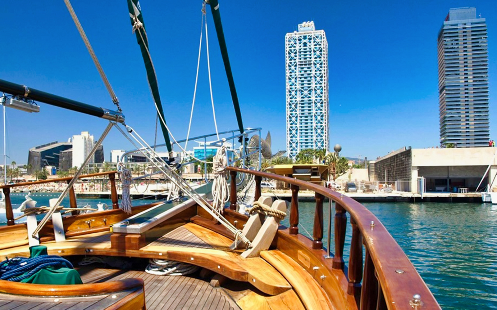 Boat deck view with Barcelona skyline, featuring iconic towers and waterfront.