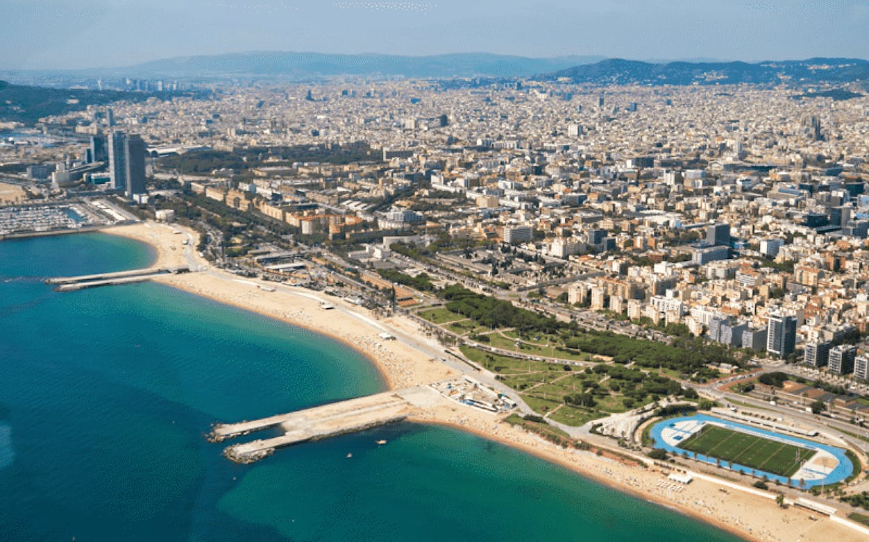 Aerial view of Barcelona's coastline with beaches and cityscape during a helicopter tour.