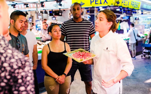 Local chef guiding a group through a Barcelona market food tour.