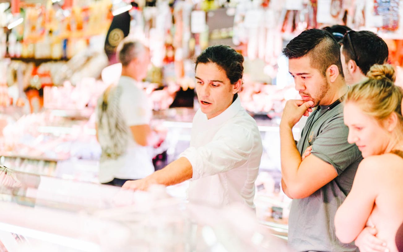 Local chef guiding tourists through a vibrant market in Barcelona.