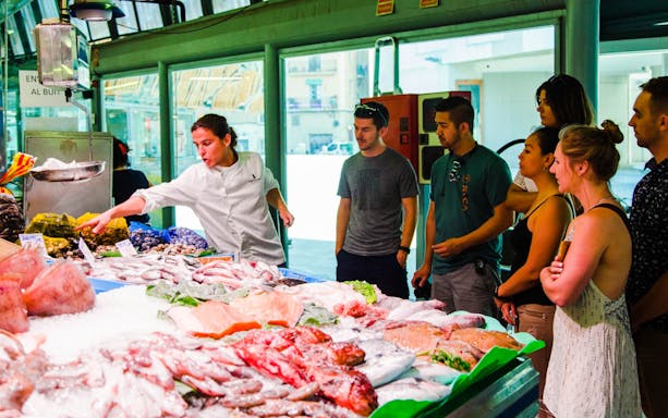 Local chef guiding a group through a seafood market in Barcelona.