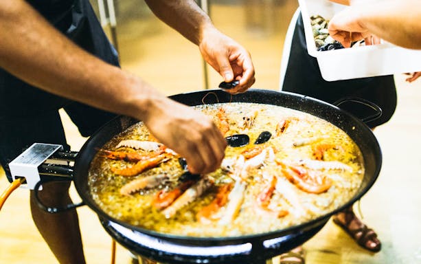 Local chef demonstrating paella cooking in Barcelona kitchen.