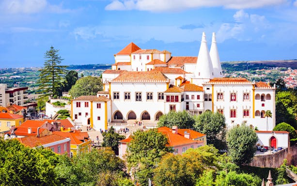 Pena Palace in Sintra with red rooftops and lush greenery, seen on a half-day tour from Lisbon.