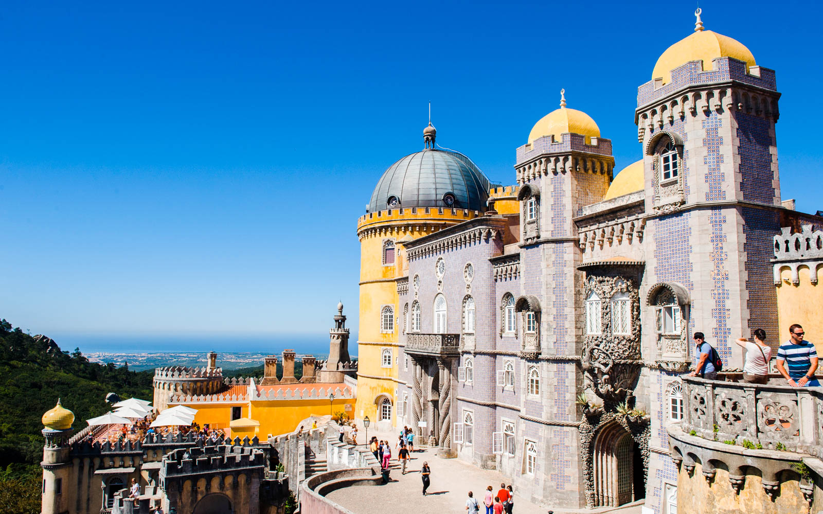 Pena Palace in Sintra with tourists exploring the colorful architecture.
