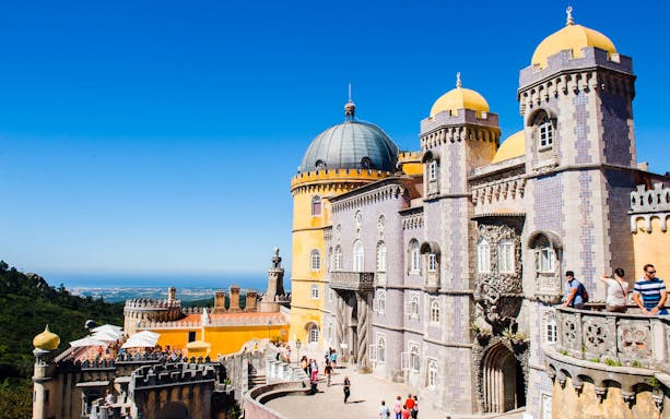 Pena Palace in Sintra with tourists exploring the colorful architecture.