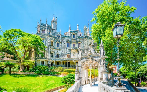 Quinta da Regaleira entrance with ornate stonework and lush gardens, Sintra, Portugal.