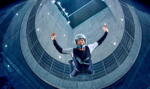 Indoor skydiving experience at Clymb Abu Dhabi, showcasing a participant in a vertical wind tunnel.