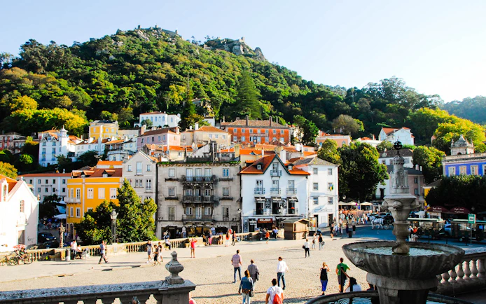Sintra town square with colorful buildings and lush hillside, Portugal.