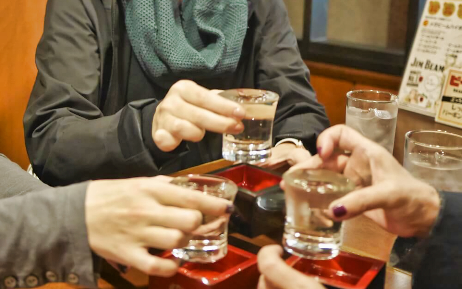 People toasting with sake glasses during Kyoto Pontocho food tour.