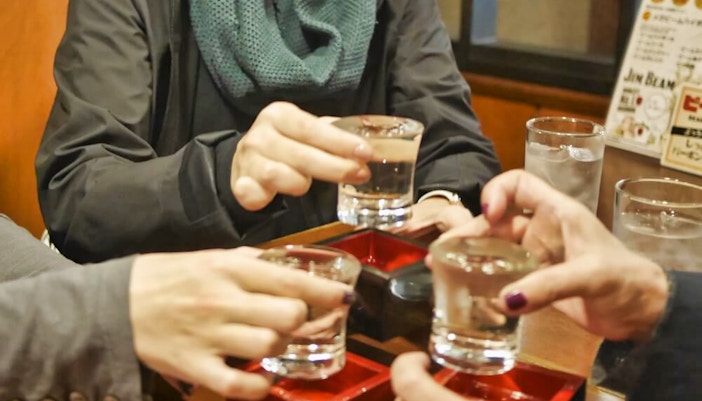 People toasting with sake glasses during Kyoto Pontocho food tour.