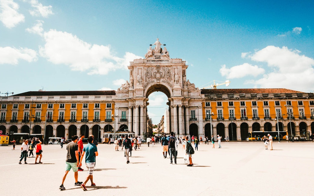 Lisbon's Rua Augusta Arch with tourists in Praça do Comércio.