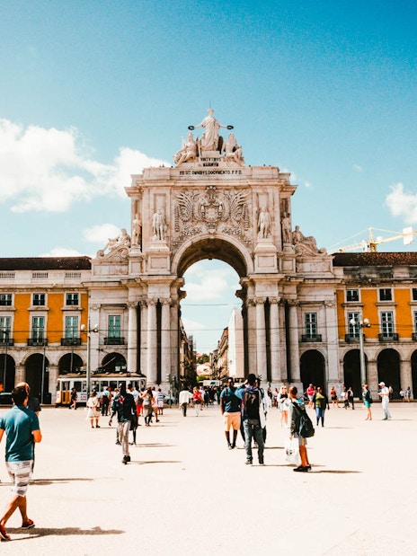 Lisbon's Rua Augusta Arch with tourists in Praça do Comércio.