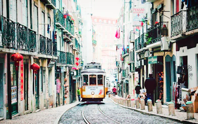 Lisbon tram on a narrow street, part of the Lisbon Card and Hop-On Hop-Off Bus Tour.