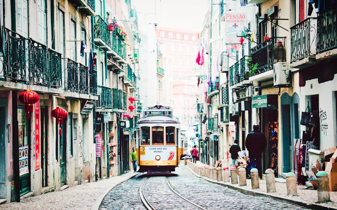 Lisbon tram on a narrow street, part of the Lisbon Card and Hop-On Hop-Off Bus Tour.