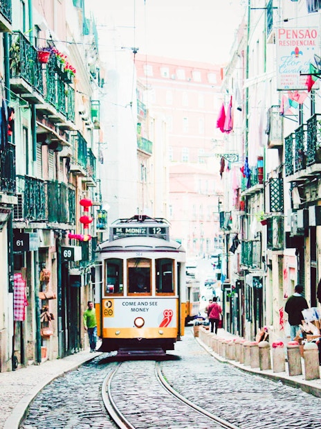 Lisbon tram on a narrow street, part of the Lisbon Card and Hop-On Hop-Off Bus Tour.