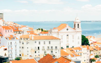 Lisbon cityscape with red rooftops and ocean view, seen on a hop-on hop-off bus tour.