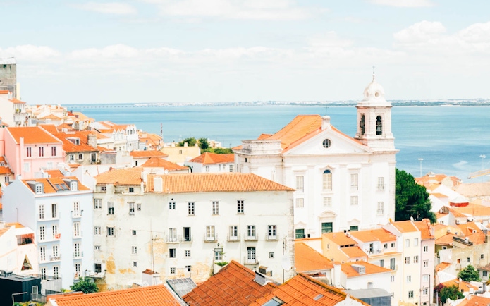 Lisbon cityscape with red rooftops and ocean view, seen on a hop-on hop-off bus tour.