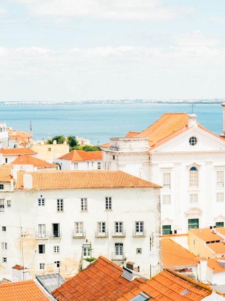 Lisbon cityscape with red rooftops and ocean view, seen on a hop-on hop-off bus tour.