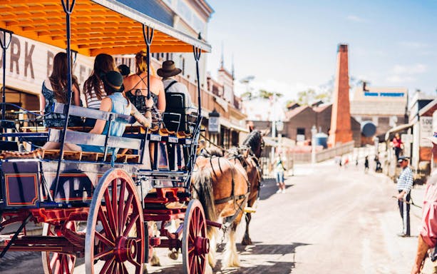 Horse-drawn carriage with tourists on a historic street at Sovereign Hill.