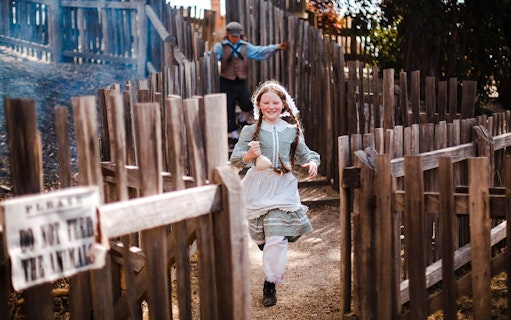 Girl running with a pouch through wooden fences at Sovereign Hill.
