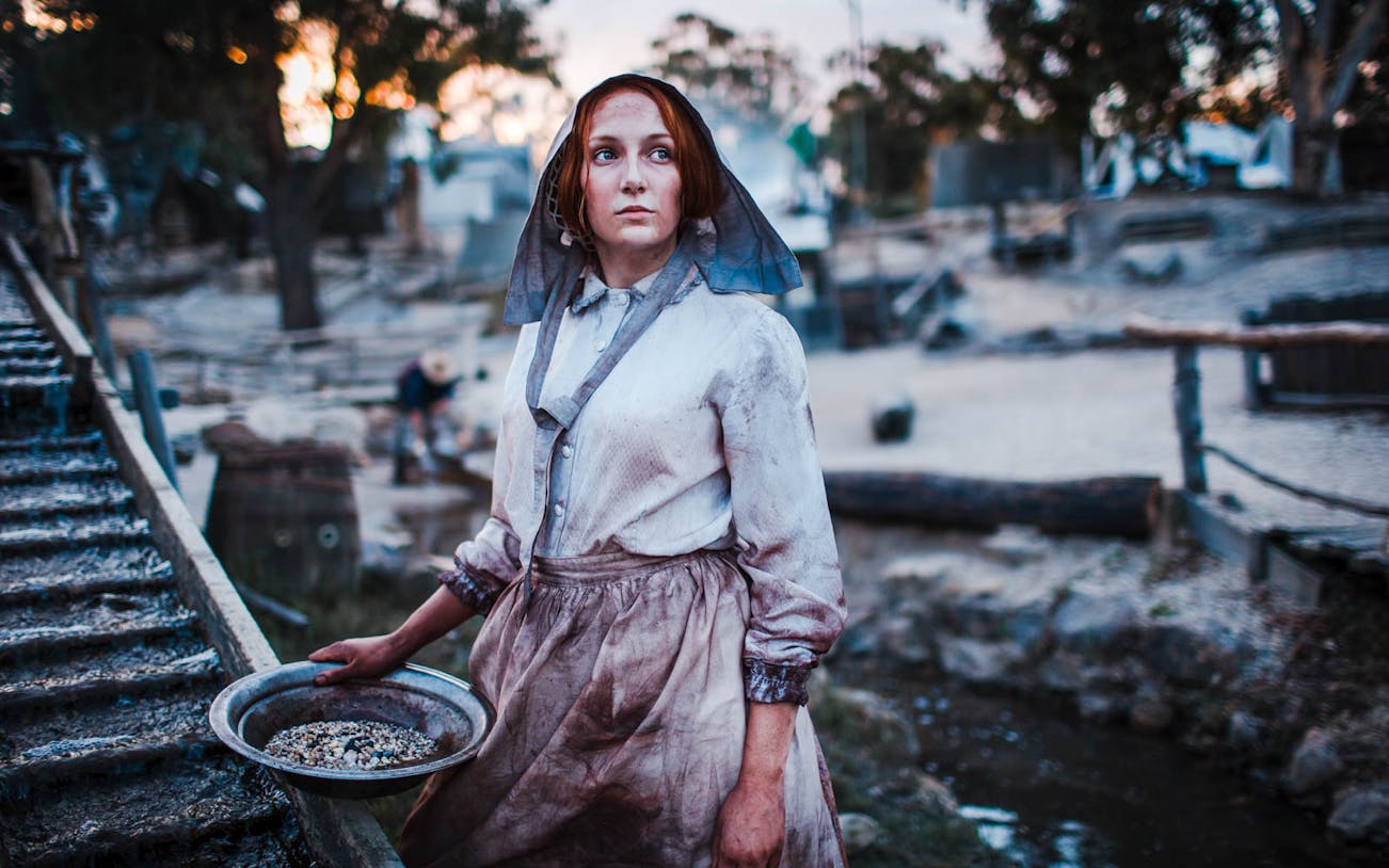 Woman in period costume panning for gold at Sovereign Hill, Australia.