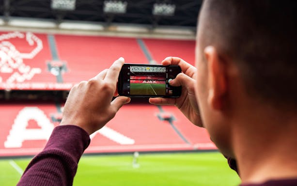 Person photographing Johan Cruijff Arena interior in Amsterdam.