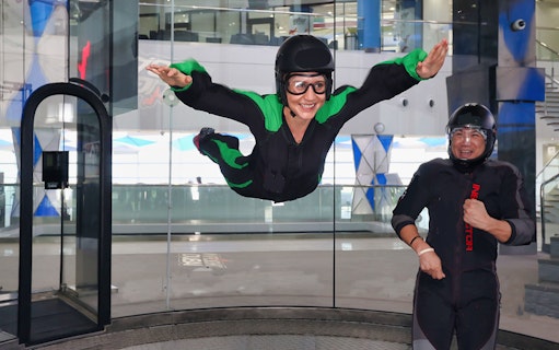 Person indoor skydiving at In Flight Dubai with instructor nearby.
