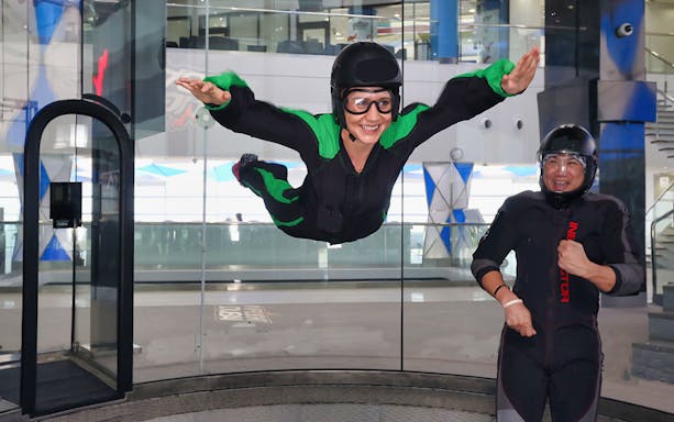 Person indoor skydiving at In Flight Dubai with instructor nearby.