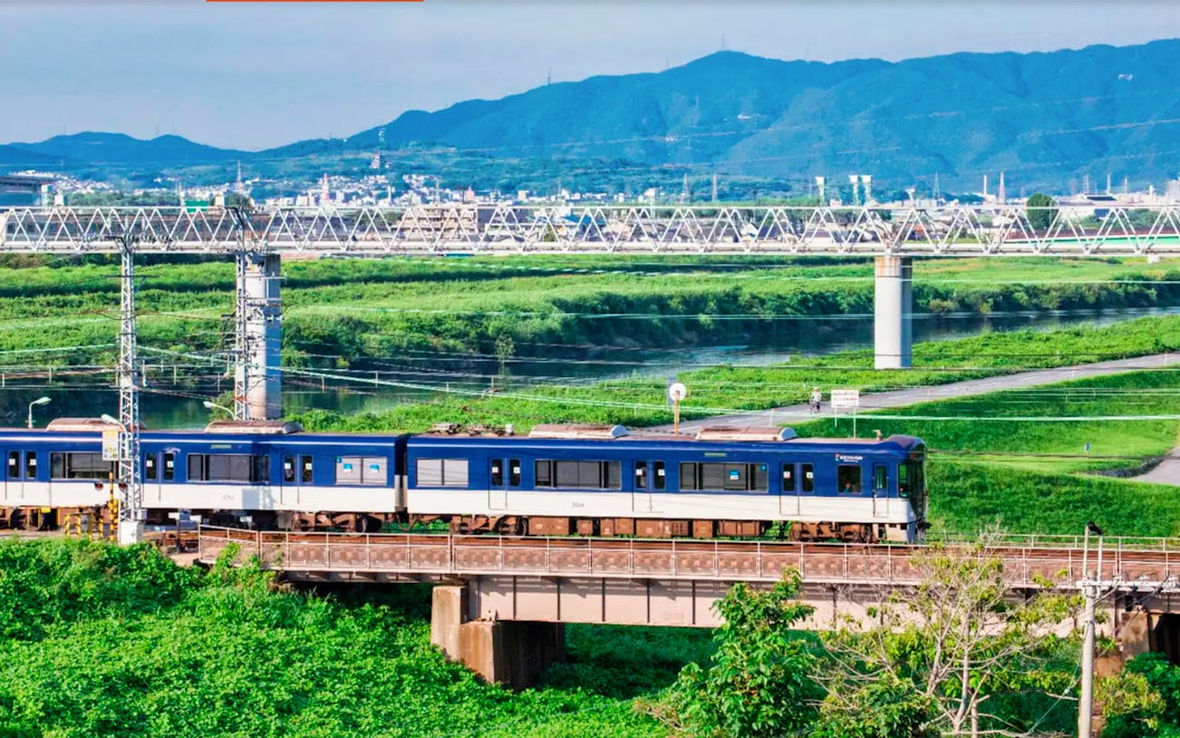 Train crossing a bridge with mountains in the background, Kyoto-Osaka Sightseeing Pass.