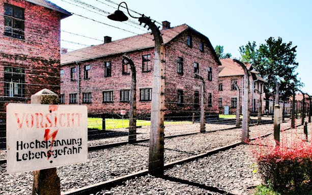 Auschwitz-Birkenau Museum barbed wire fence and brick buildings.
