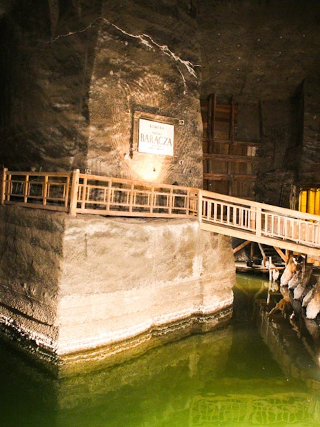 Wieliczka Salt Mine underground chamber with wooden walkway and illuminated salt formations.