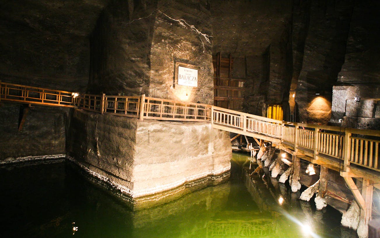 Wieliczka Salt Mine underground chamber with wooden walkway and illuminated salt formations.