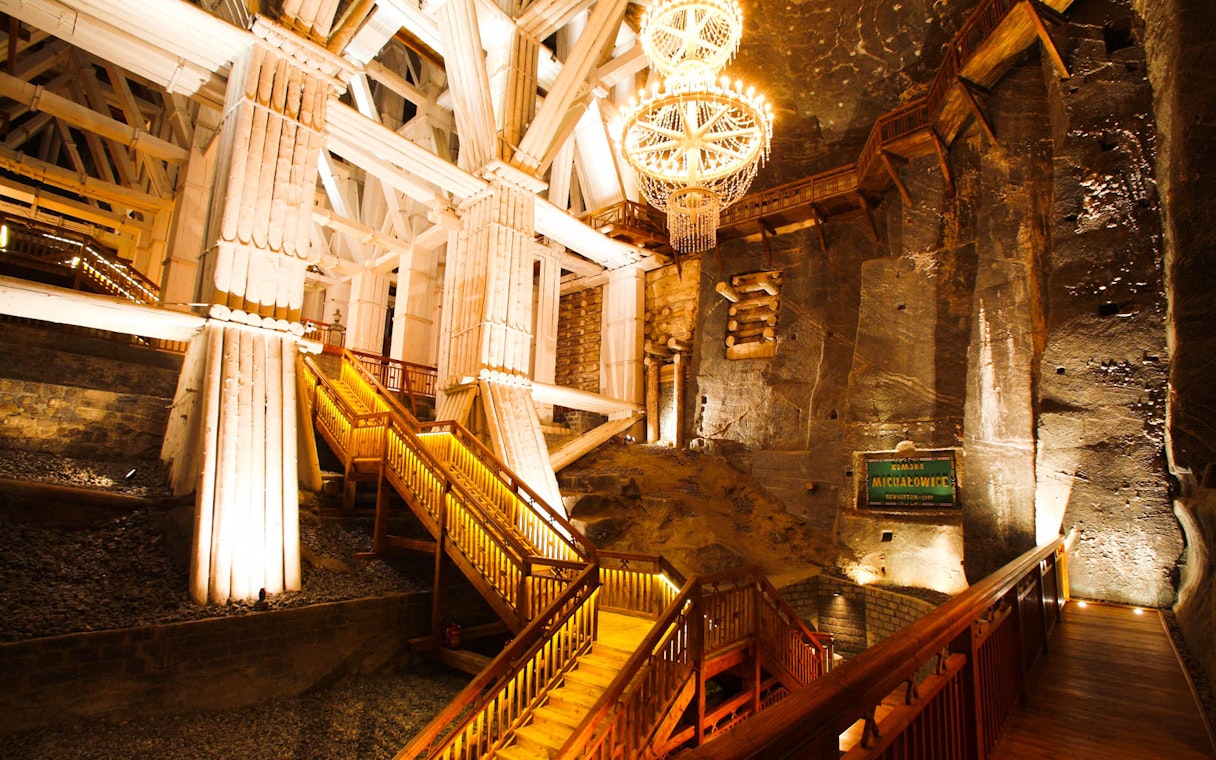 Wieliczka Salt Mine interior with illuminated wooden stairs and chandelier.
